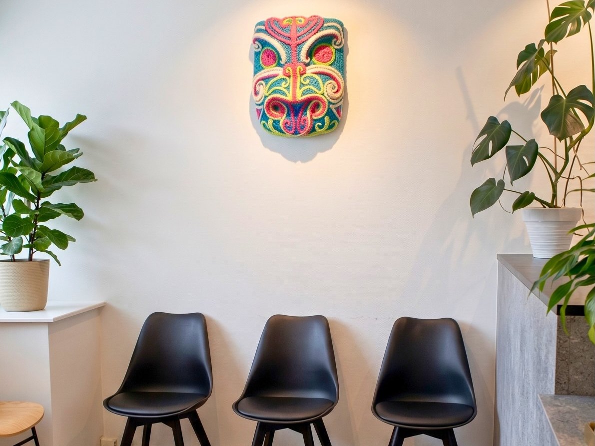 The waiting area at The Healing Centre Remuera: three chairs beneath a colourful woven mask, with plants on either side